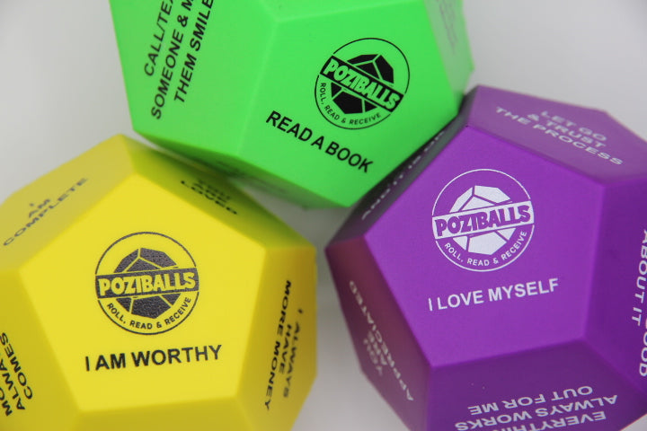 Three Dodecahedron-shaped stress ball in three colors green, yellow and purple with 'Poziballs' branding and text in black and white letters on twelve sides